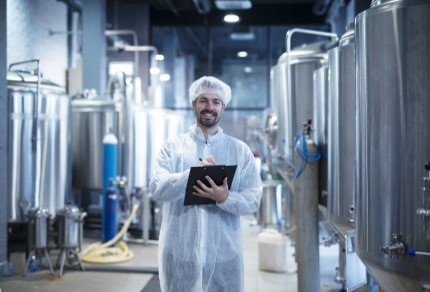 food-processing-plant-interior-with-positive-smiling-technologist-holding-checklist